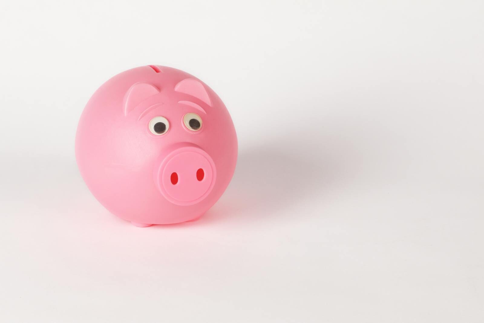 A cute pink piggy bank with googly eyes on a white background, symbolizing savings and finance.