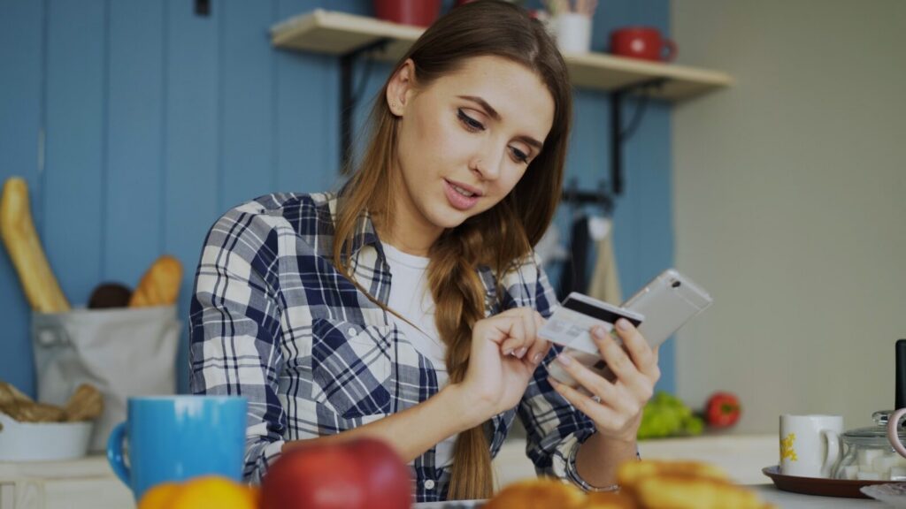 Woman using credit card with smartphone at table