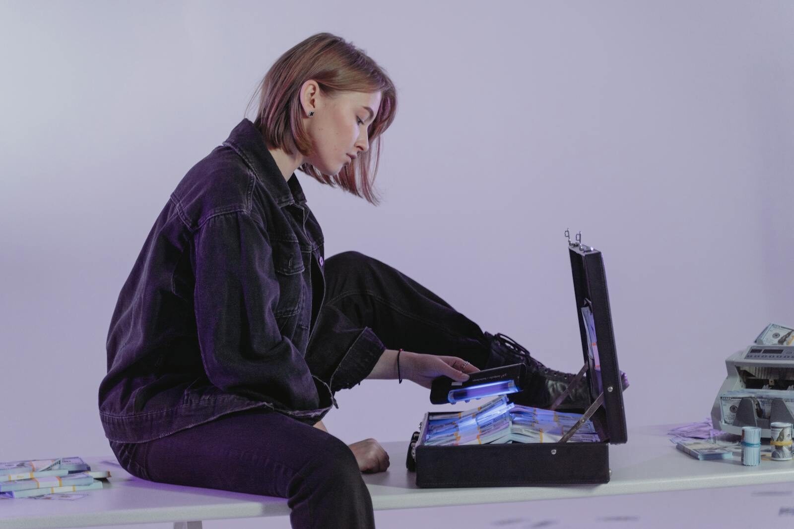 A woman examining cash in a briefcase, hinting at modern financial themes indoors.