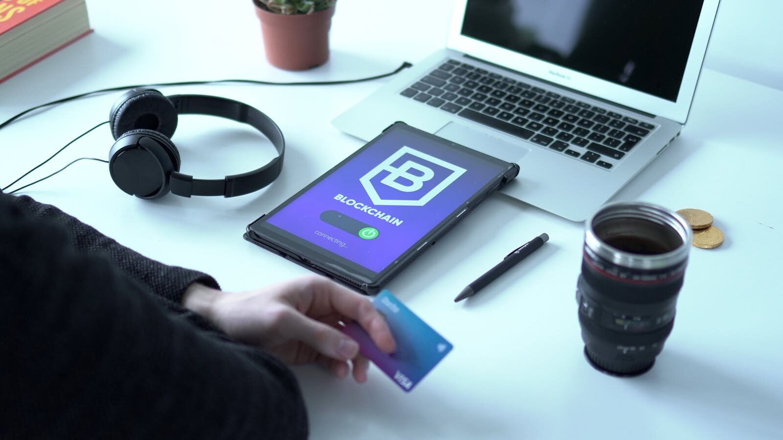 Modern workspace featuring blockchain technology. Laptop, tablet, and card on a desk.