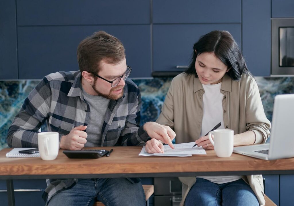 Interracial couple discussing bills and financial planning in a cozy indoor setting.