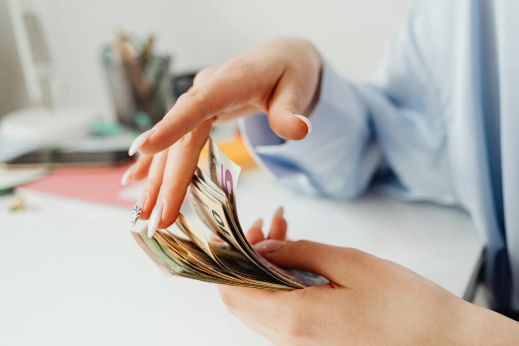 Close-up of a woman's hand counting euro banknotes on the office desk.