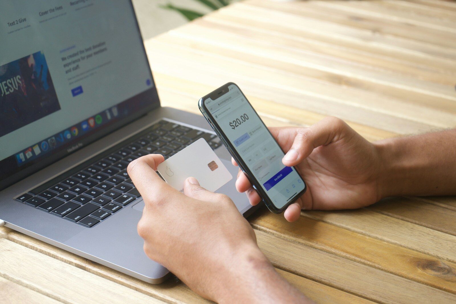 Person using smartphone and credit card with laptop