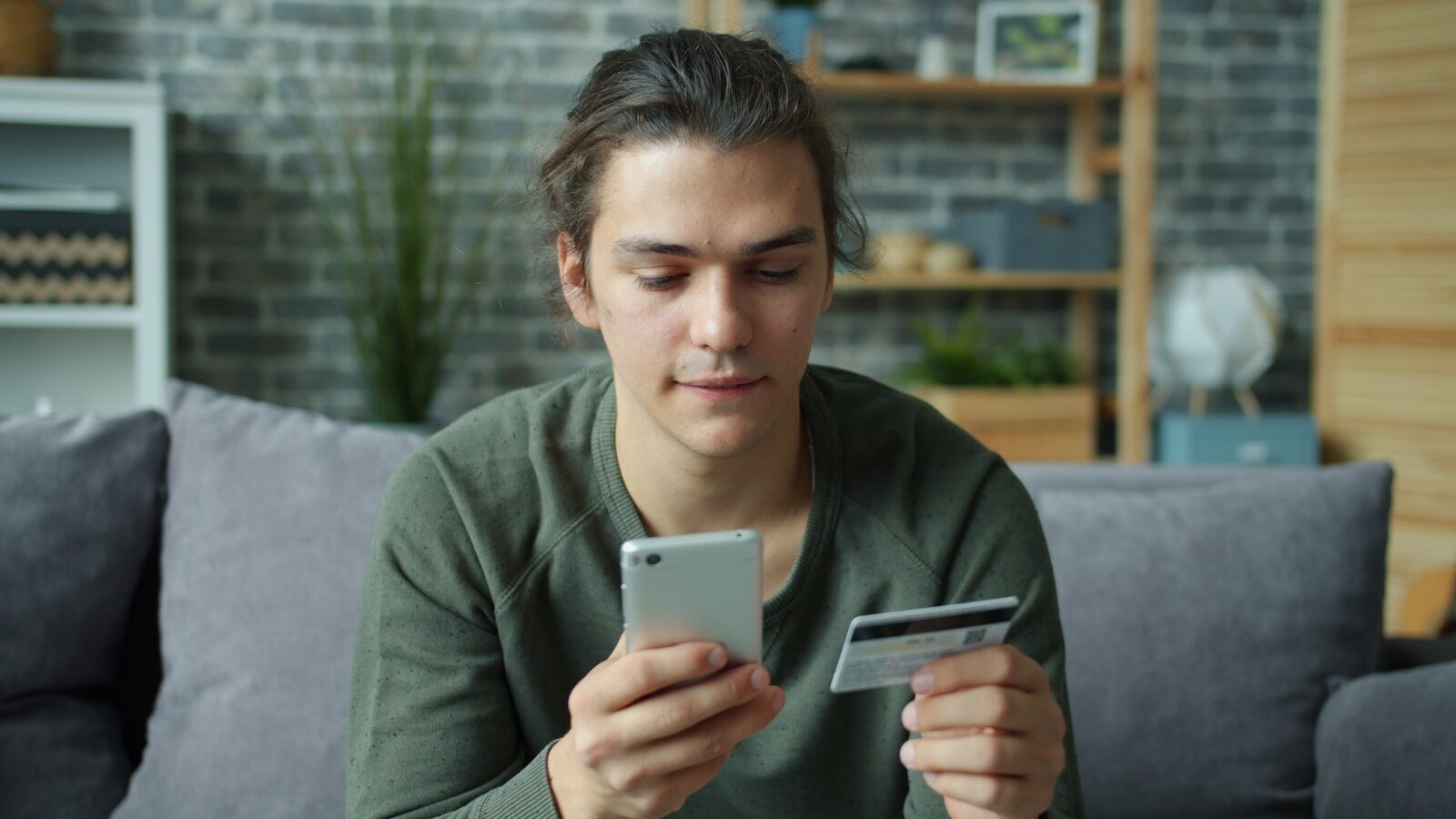 Young man using smartphone and credit card for online shopping