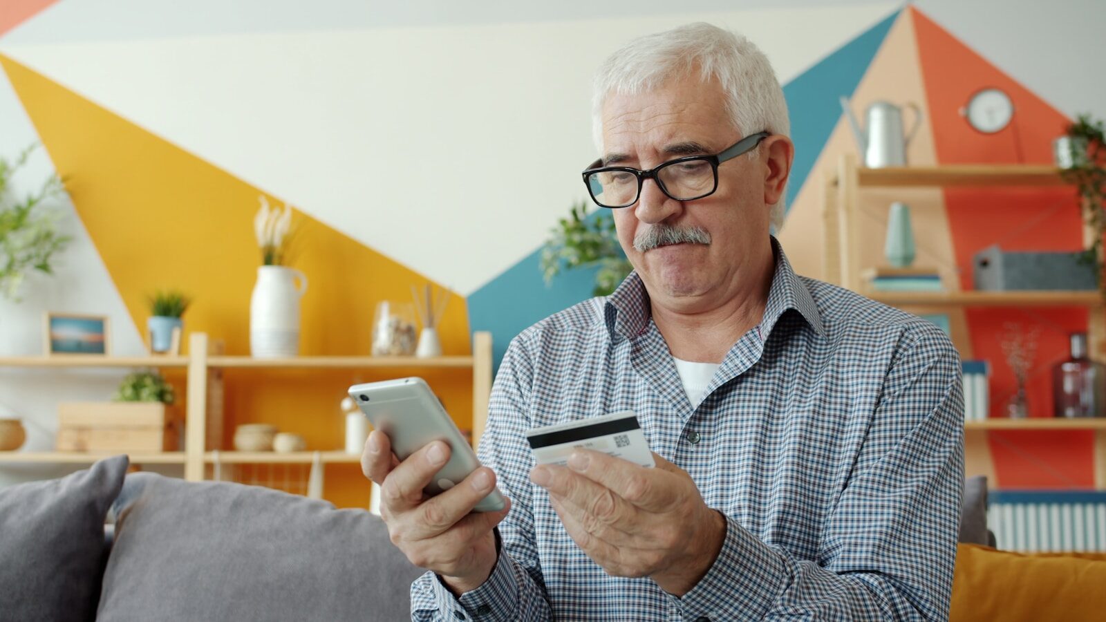 Elderly man using smartphone and credit card for online shopping