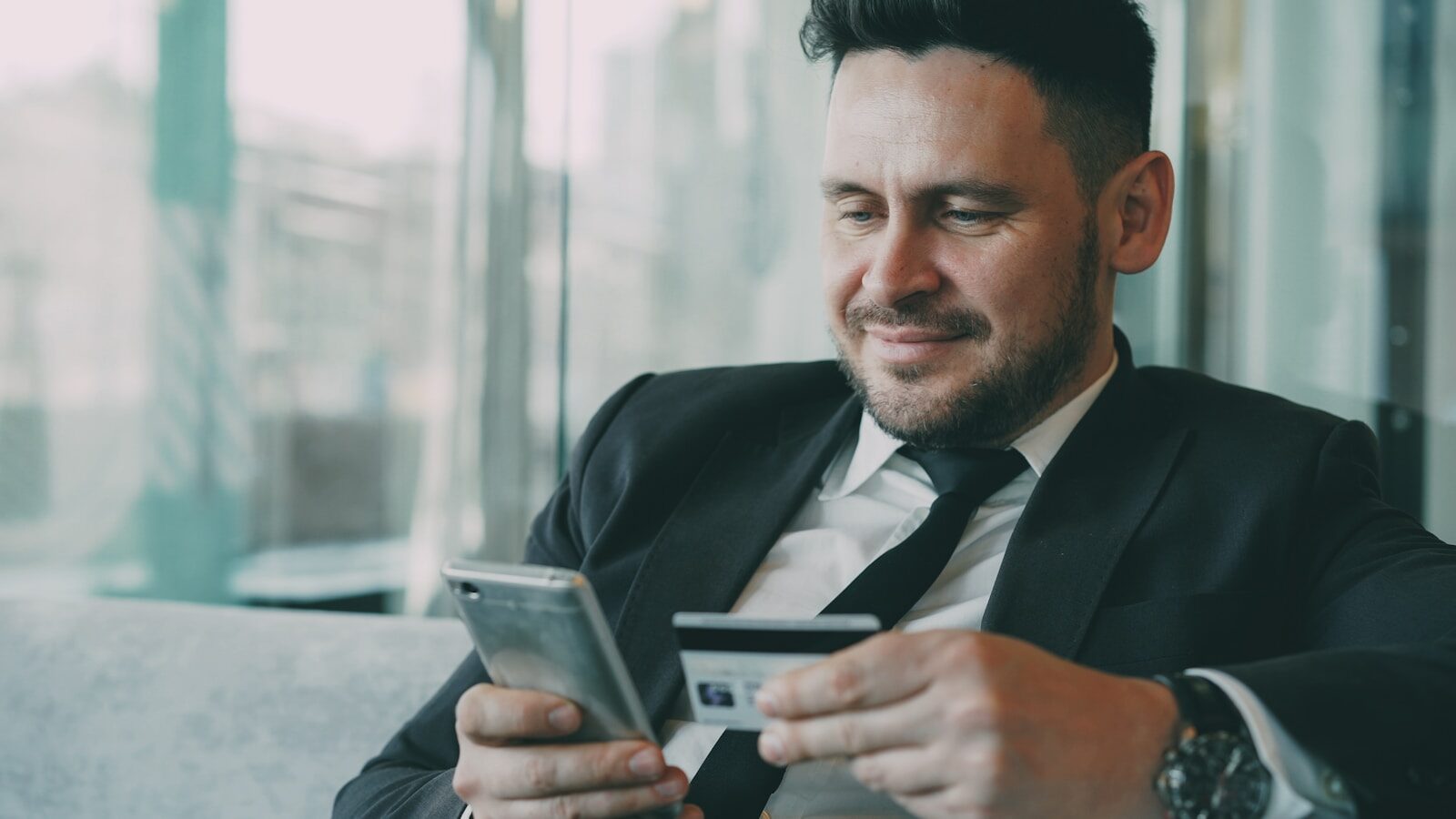 Man in suit using smartphone and credit card