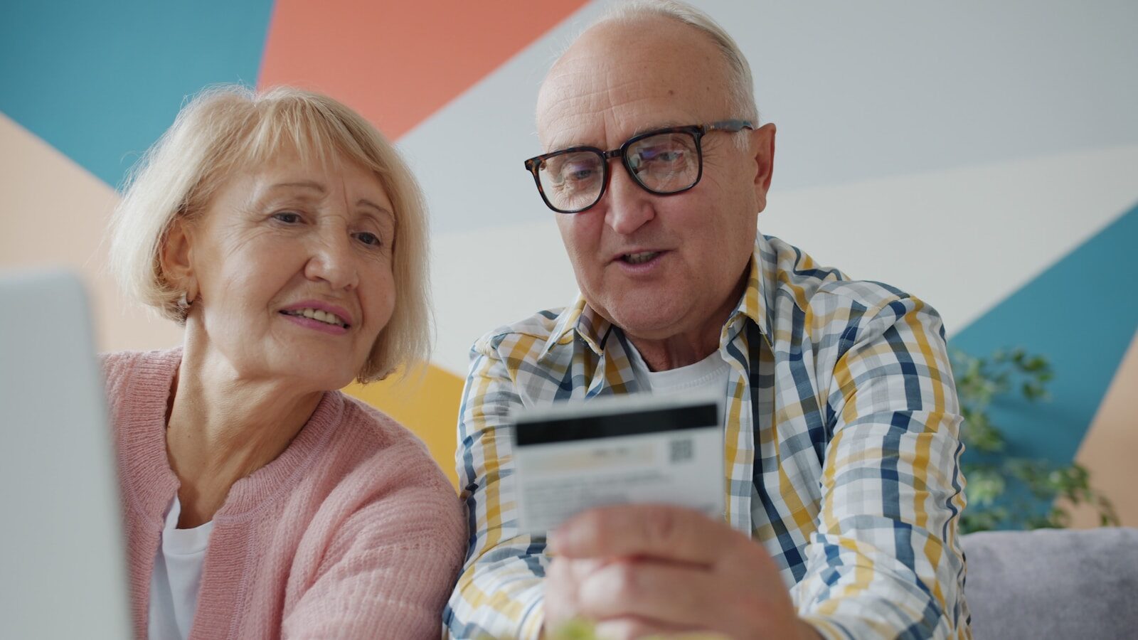 Elderly couple looking at credit card and laptop